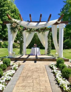 A white wedding ceremony set up in a garden.