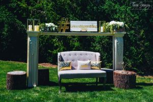 A gold and white wedding set up with a chair and tree stumps.