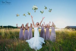 Bridesmaids throwing bouquets in a field.