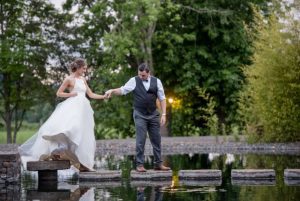 An Oregon bride and groom standing on steps near a pond at an outdoor wedding venue.