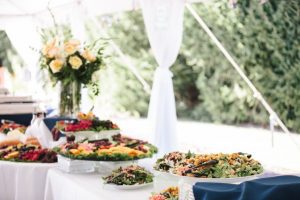 A buffet table with a variety of salads and desserts at an outdoor Oregon wedding venue.