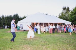 A bride and groom dancing in front of a white tent.
