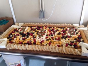 A large platter of fruit and cheese on a table.