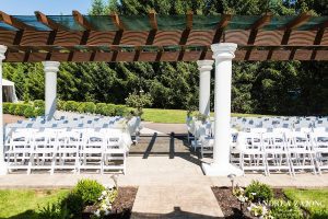 An outdoor wedding ceremony set up with white chairs.