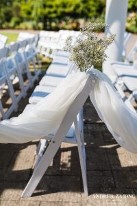 A wedding ceremony set up with white chairs and flowers.