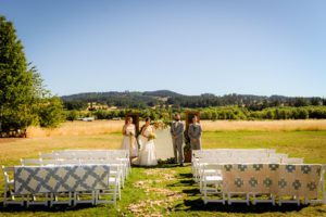 A wedding ceremony set up in a field with chairs and blankets.