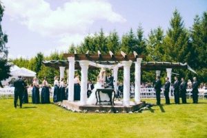 A wedding ceremony under a gazebo in a grassy area.
