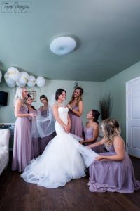 A bride and her bridesmaids are getting ready in a room.