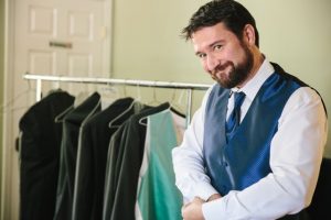 A man standing in front of a rack of suits.