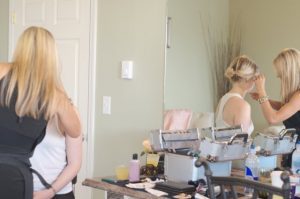 A woman getting her makeup done in front of a mirror.