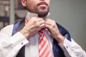 A man adjusting his tie in front of a mirror.