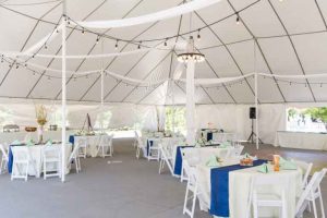 A white tent with blue and white tables and chairs.