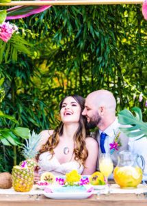A bride and groom sitting at a tropical wedding table.