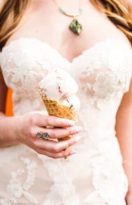 A woman in a white dress holding an ice cream cone.