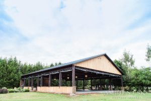 A barn in the middle of a field with trees.