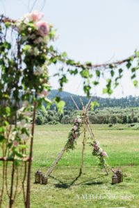 A teepee in the middle of a field with flowers.