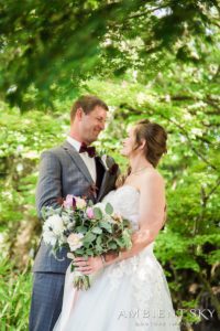 A bride and groom standing in a wooded area.