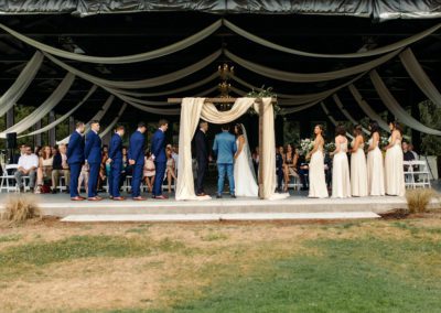 The bride and groom at the wedding arch with their attendants