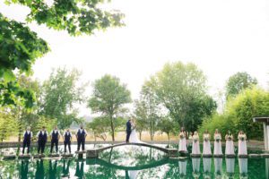 Newlyweds and their attendants on stepping stones and a bridge