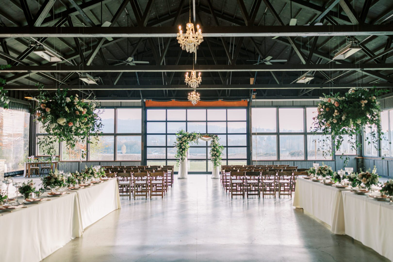 The Water Oasis Arbor draped with white chiffon, a chandelier and hanging flower baskets.