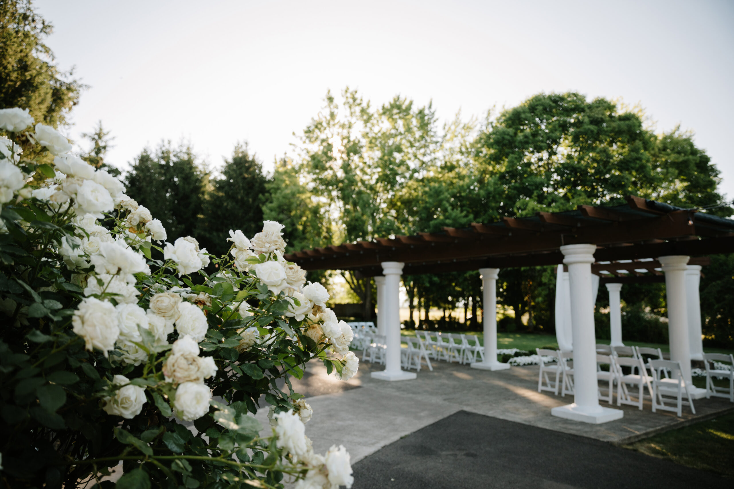 The Water Oasis Arbor draped with white chiffon, a chandelier and hanging flower baskets.