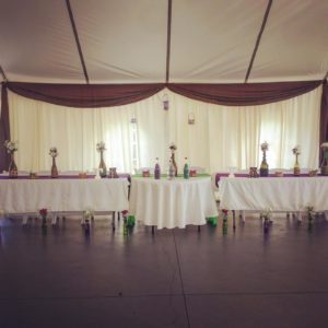 A table set up in a tent with vases on it.