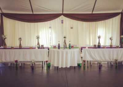 A table set up in a tent with vases on it.