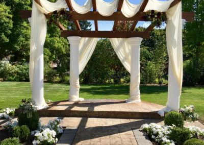 A wedding ceremony set up with white drapes and flowers.