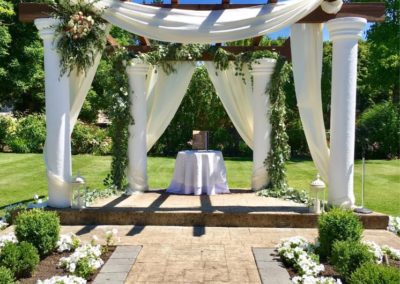 A white wedding ceremony set up in a garden.