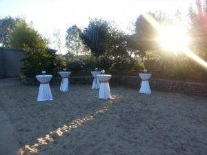 A table set up in the sand with white linens.