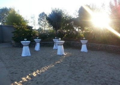 A table set up in the sand with white linens.