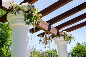 A white pillar with flowers hanging from it.