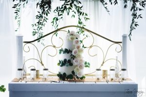A wedding cake sitting on top of a table with greenery.