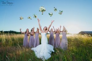 Bridesmaids throwing bouquets in a field.