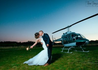 Newlyweds kiss near a helicopter