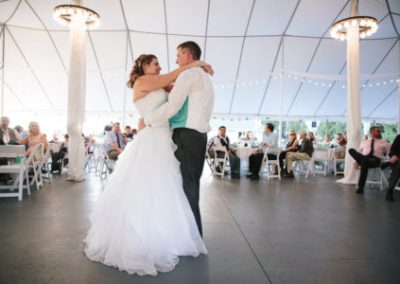 A bride and groom sharing their first dance under a tent.