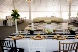 An elegant outdoor wedding venue in Oregon, featuring a spacious white tent adorned with black and white striped tablecloths.