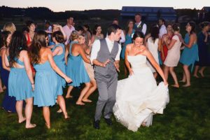 A bride and groom dancing on a grassy field.