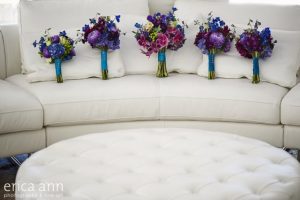 Four bouquets are sitting on a white couch.