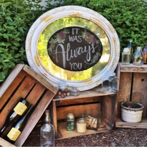 A wooden crate with a bottle of wine and a sign that says it was always you.