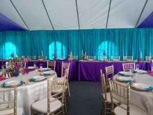 A blue and purple tent with tables and chairs.