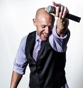 A bald man holding a microphone.
