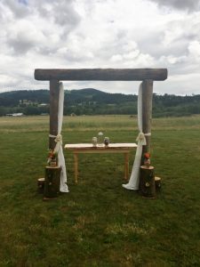 A wooden arch in the middle of a field.