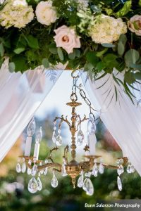 A wedding ceremony with a chandelier and flowers.
