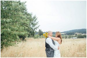 A bride and groom embracing in a field with sunflowers.