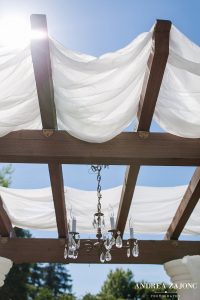 An arbor covered in white fabric with a chandelier.