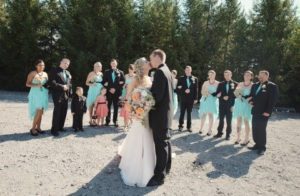 A bride and groom with their wedding party in a gravel field.