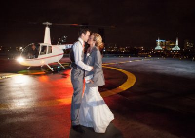 A couple kissing near a parked helicopter