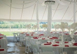 A white tent with red and white tables and chairs.