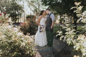 A bride and groom kissing in a garden.